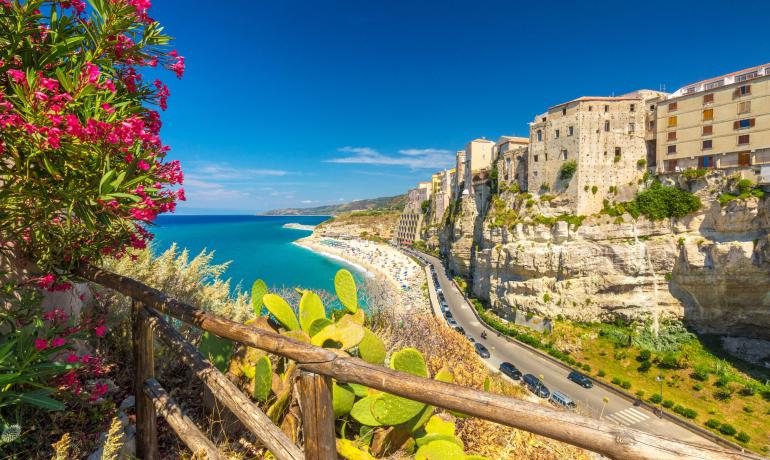 Scogliera con case storiche e mare azzurro sotto un cielo limpido.