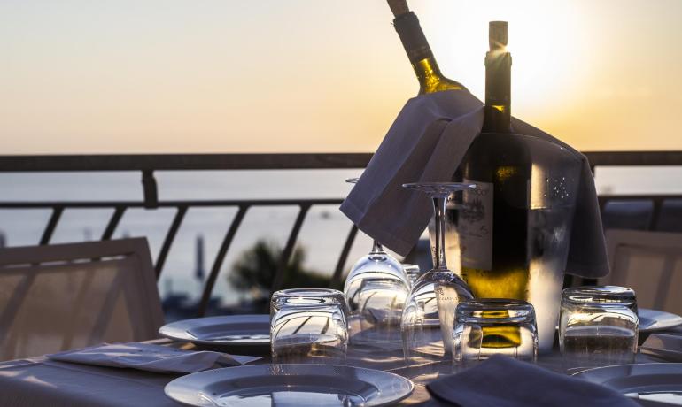 Abendessen bei Sonnenuntergang mit Wein, Gläsern und Tellern auf einem Außentisch.