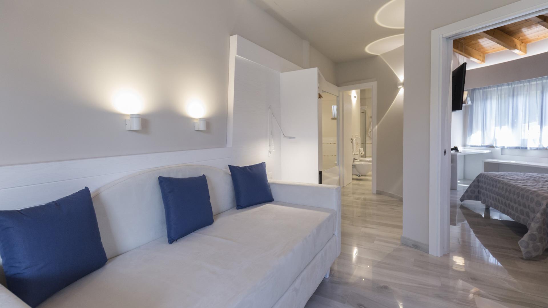 Camera moderna con divano, letto, bagno e luci soffuse.