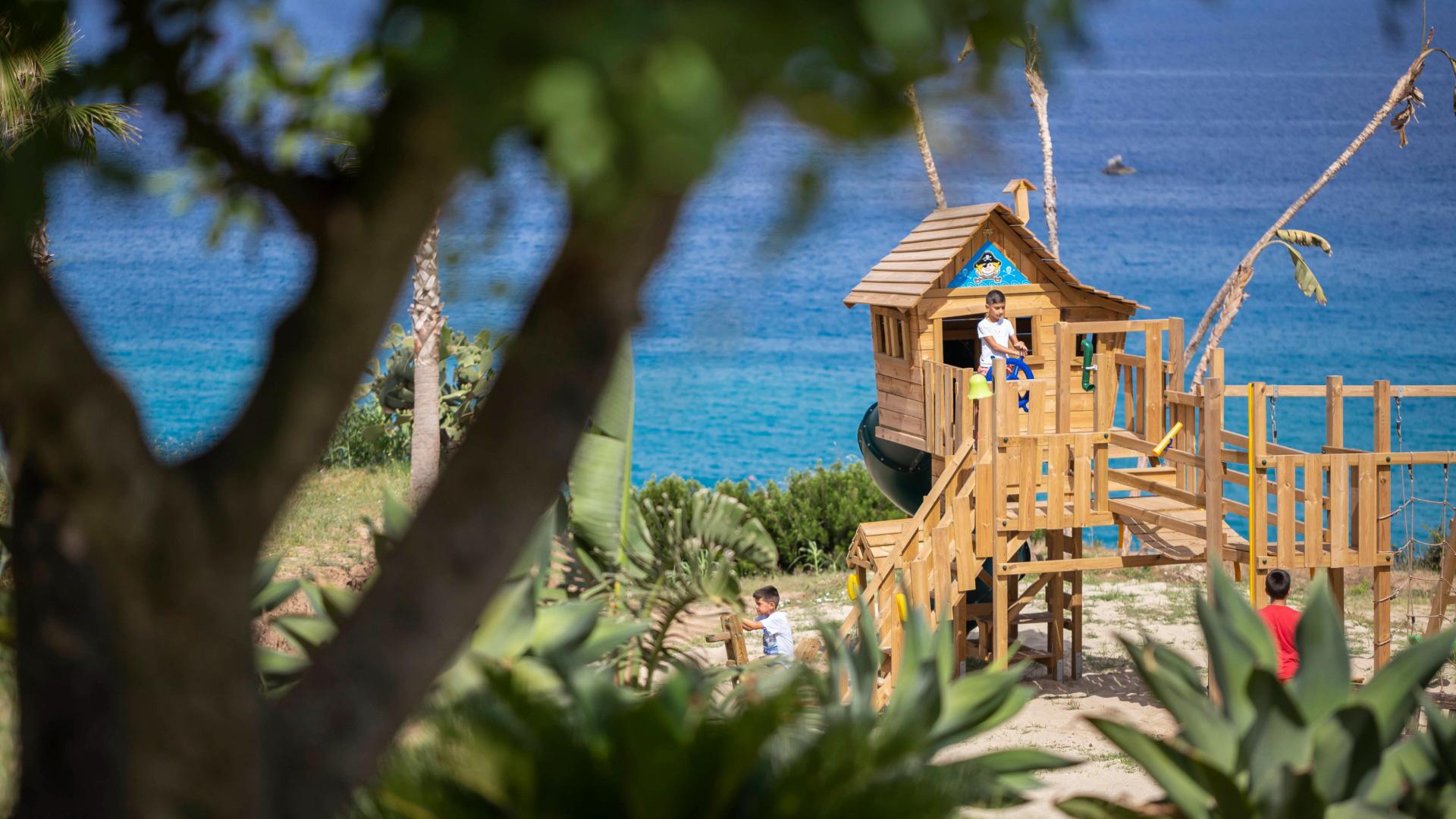 Bambini giocano in una casa sull'albero vicino al mare.