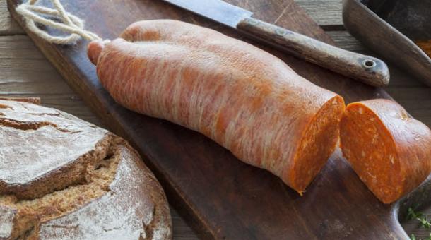 Kalabrische Soppressata mit Brot und Gewürzen auf einem Holzbrett.