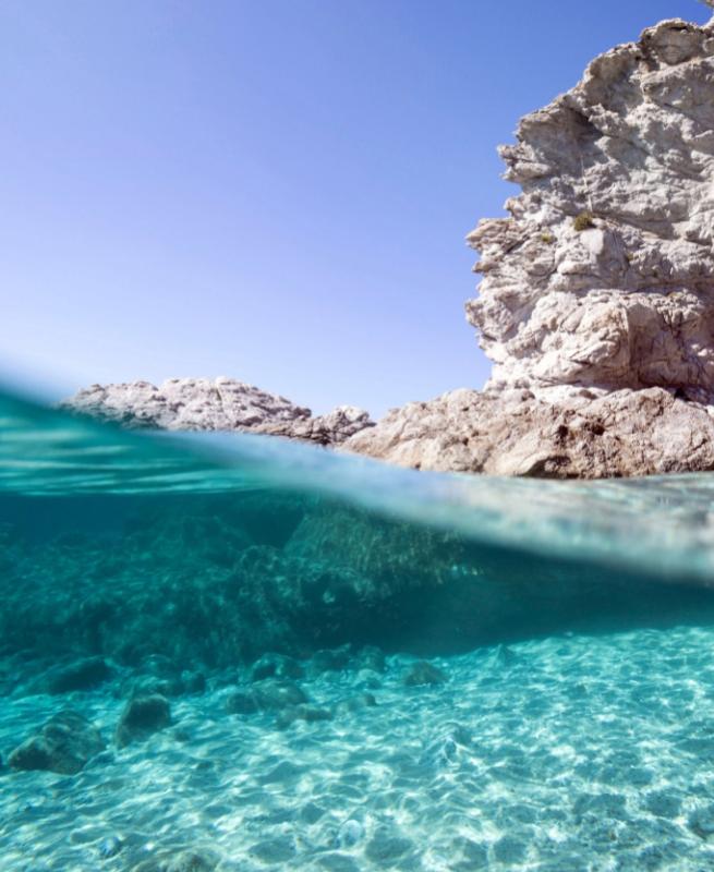 Acqua cristallina e rocce bianche sotto un cielo azzurro.
