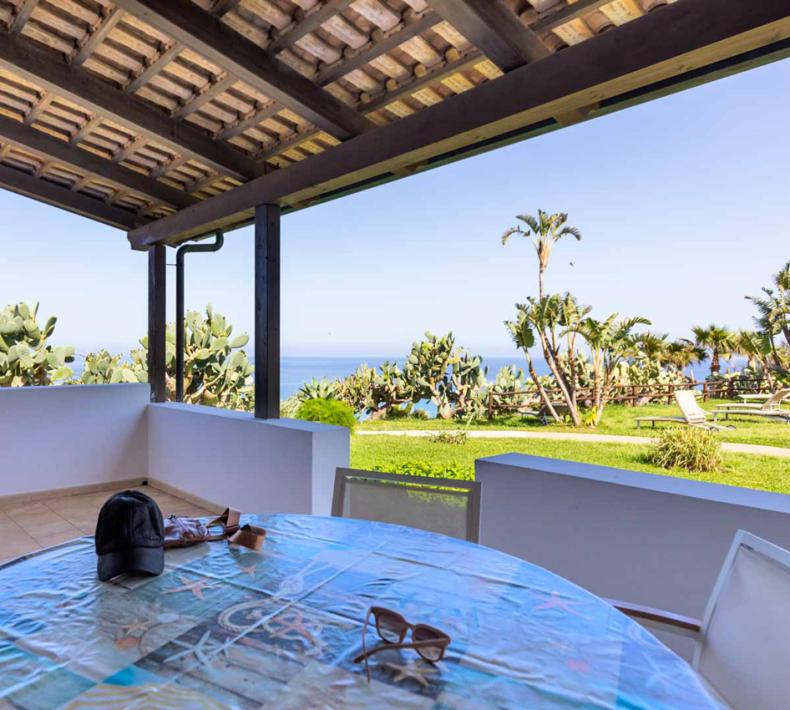 Terrace with sea view, tropical plants, and outdoor table.