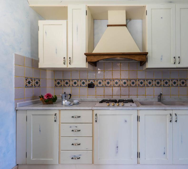 Rustic kitchen with white cabinets and decorative tiles.