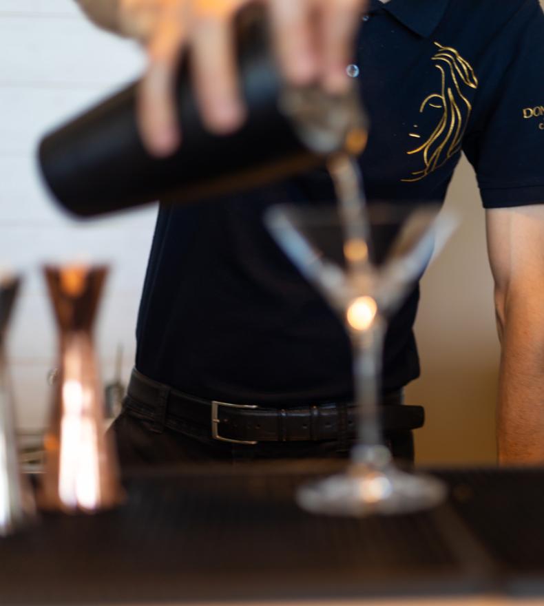 Barkeeper gießt ein Getränk in ein Cocktailglas.