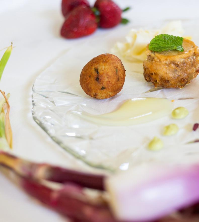 Piatto gourmet con polpette, verdure e salse, guarnito con fragole fresche.
