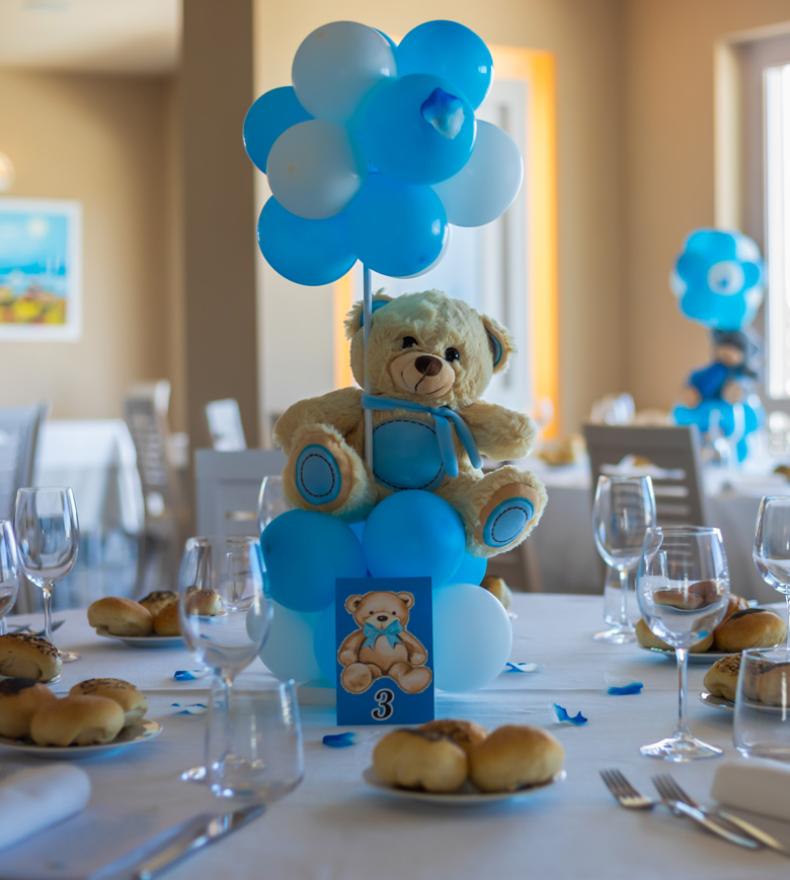 Tisch mit Teddybär und blauen Luftballons für eine Party dekoriert.